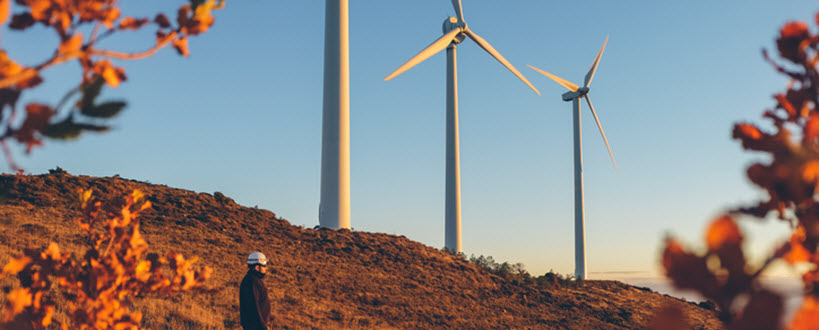 Man standing in front of three windmills.