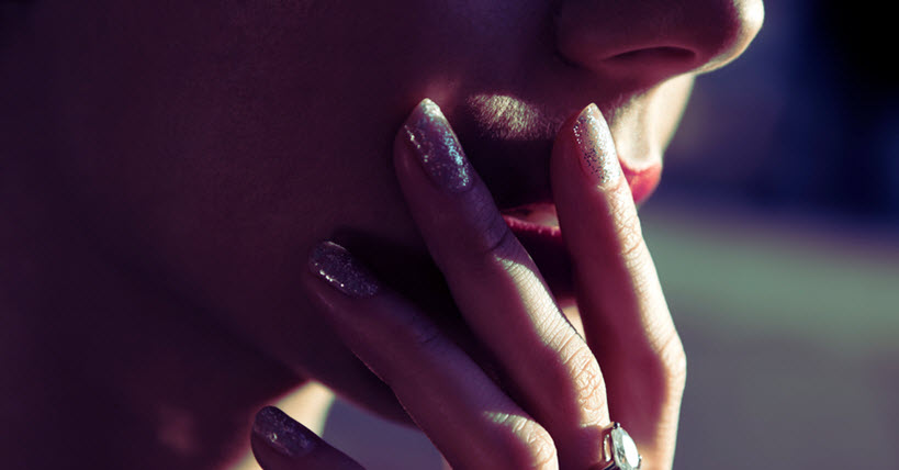 Les doigts de la main d'une femme reposent sur ses lèvres. 