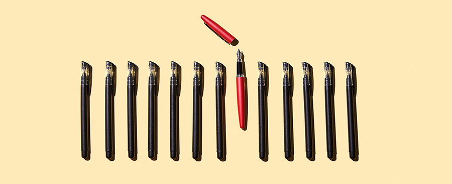 A row of pens - one with its cap off.