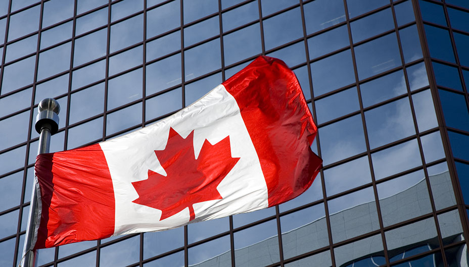 Canadian flag outside a glass building.