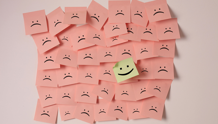 Sticky notes with sad faces. One has a happy face. 
