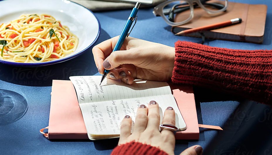 Woman taking notes at the dinner table.