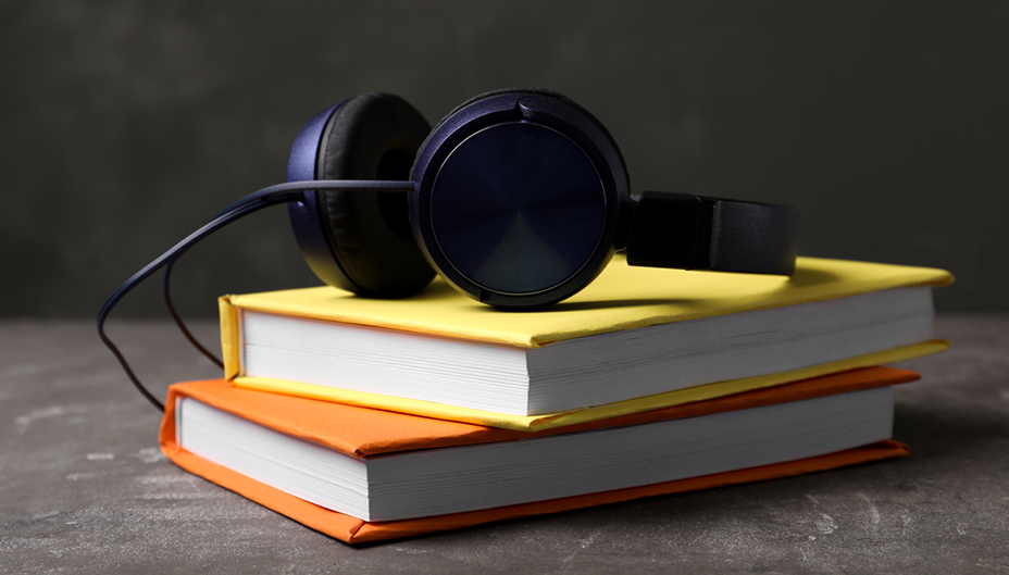 A pile of books with headphones sitting on them. 