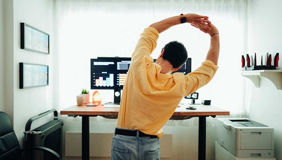 An investor stretches in front of his computer.
