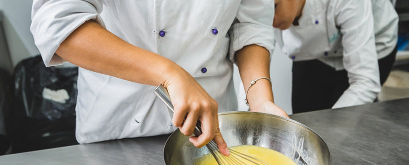 Close-up of female chef beating eggs