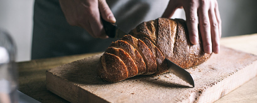 Close-up of a baker slicing a loaf of bread