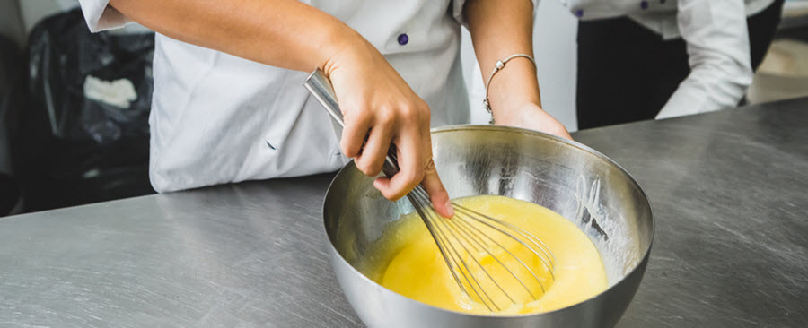 Gros plan d'une chef qui bat des œufs