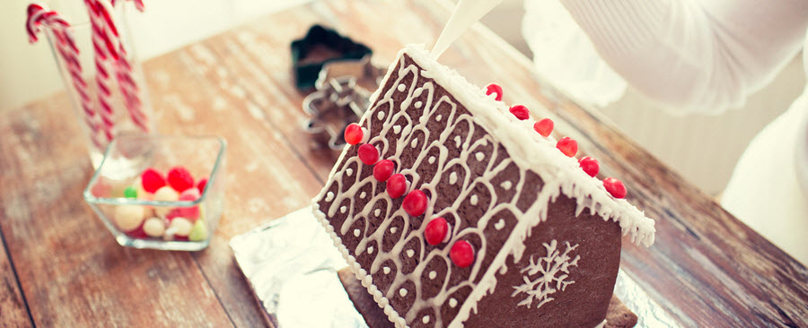 Close-up of a woman making a gingerbread house.