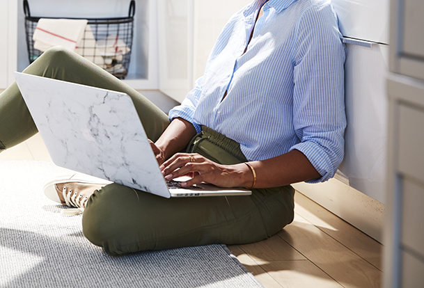 Woman on her kitchen floor working on a laptop. 