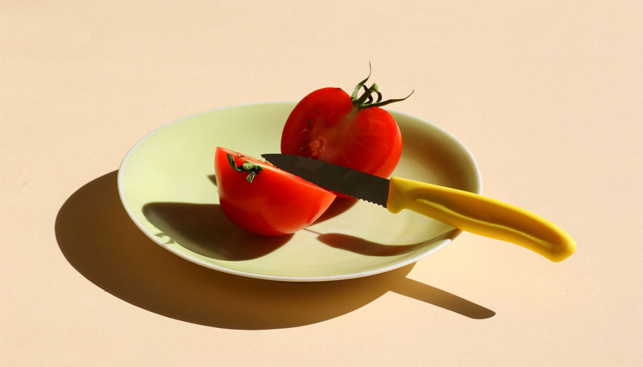 Tomato on a plate split in half with a knife.