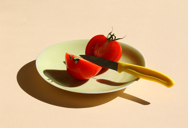 Tomato on a plate split in half with a knife.