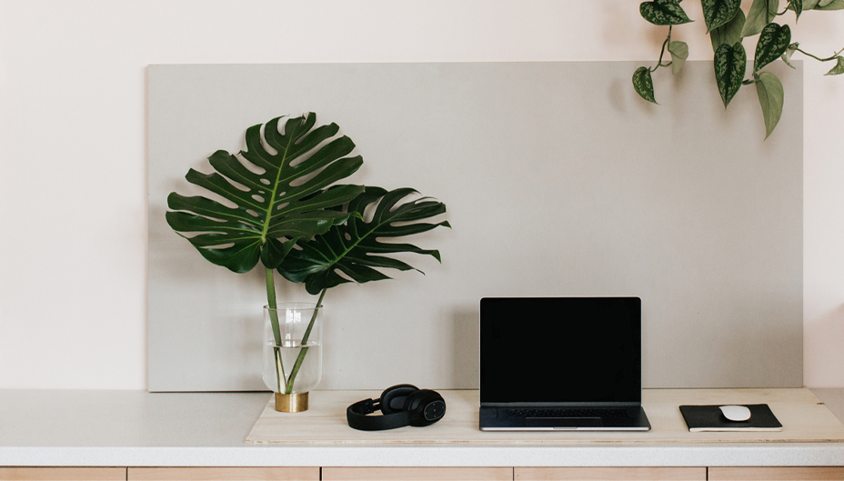 Image d’un ordinateur portable sur un bureau avec des écouteurs et une plante à côté.