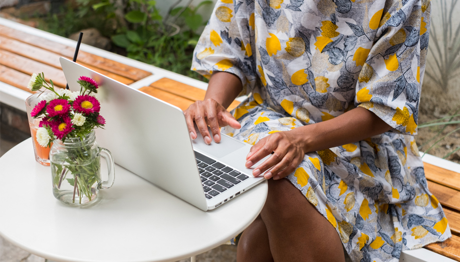 A woman sitting outside working on a laptop.