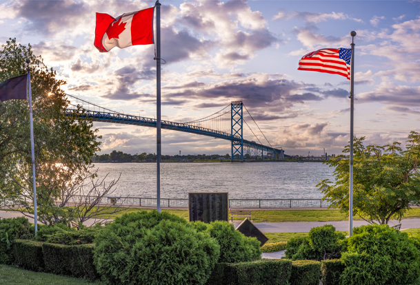 Drapeaux du Canada et des États-Unis au premier plan et pont à l’arrière-plan
