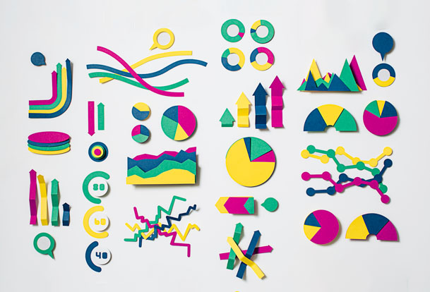 Divers symboles et graphiques de données découpés dans du papier de couleur.