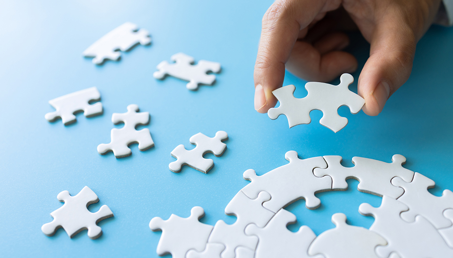 A hand holds a puzzle piece in an analogy for GICs fitting into an investor's portfolio.