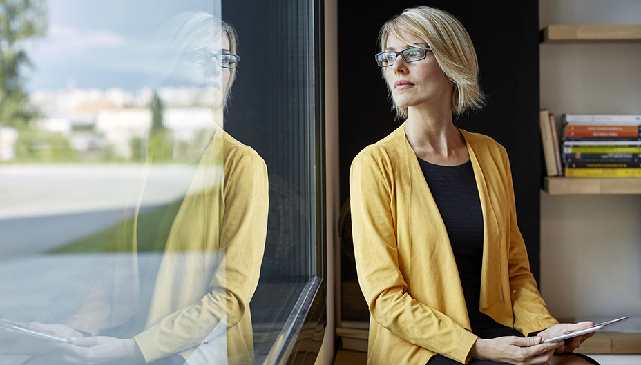 A woman contemplates investing risk as she looks out a window.