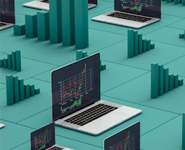 Multiple open laptops with charts on the screens sitting on a green surface