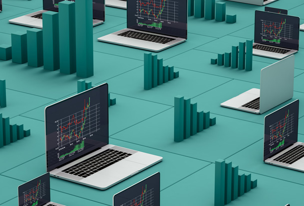 Multiple open laptops with charts on the screens sitting on a green surface
