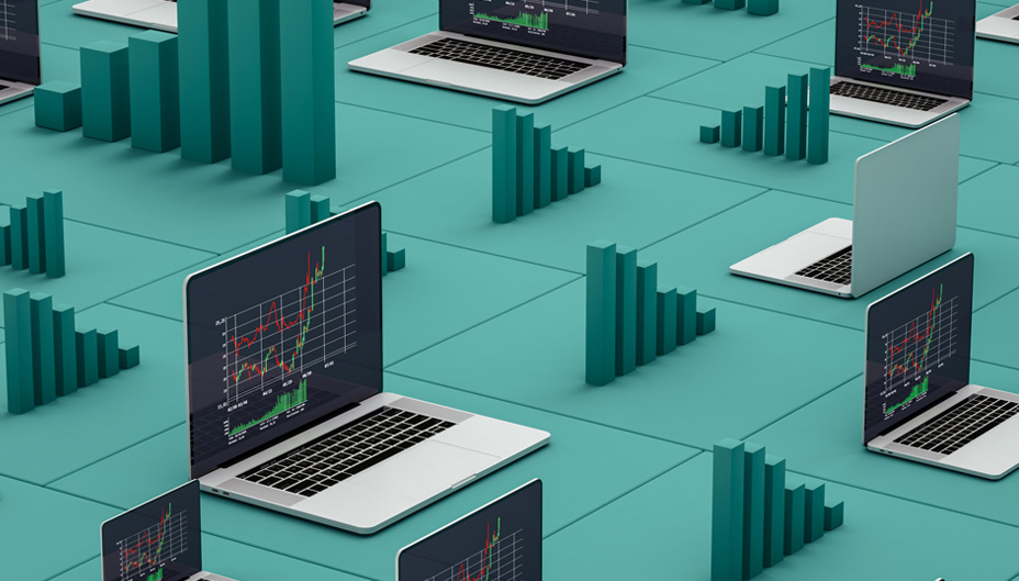 Multiple open laptops with charts on the screens sitting on a green surface