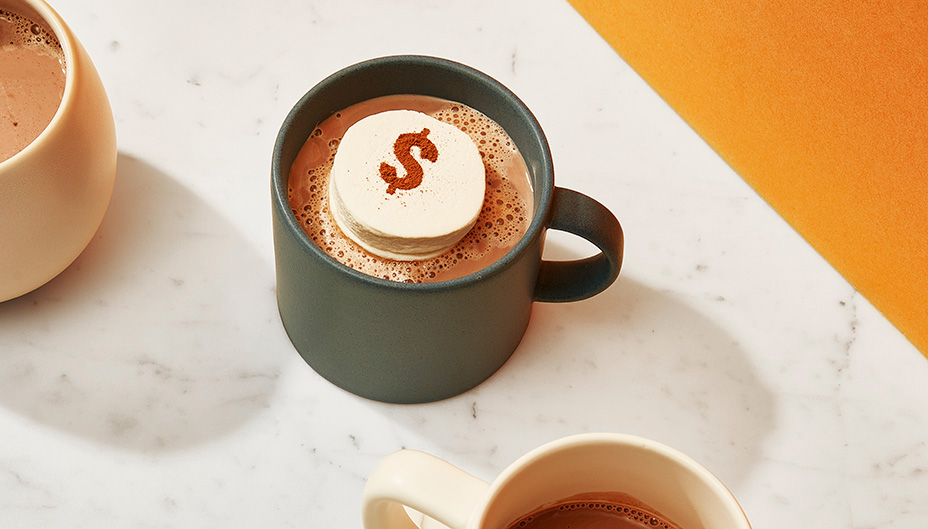 Marshmallow with dollar sign in mug of hot chocolate