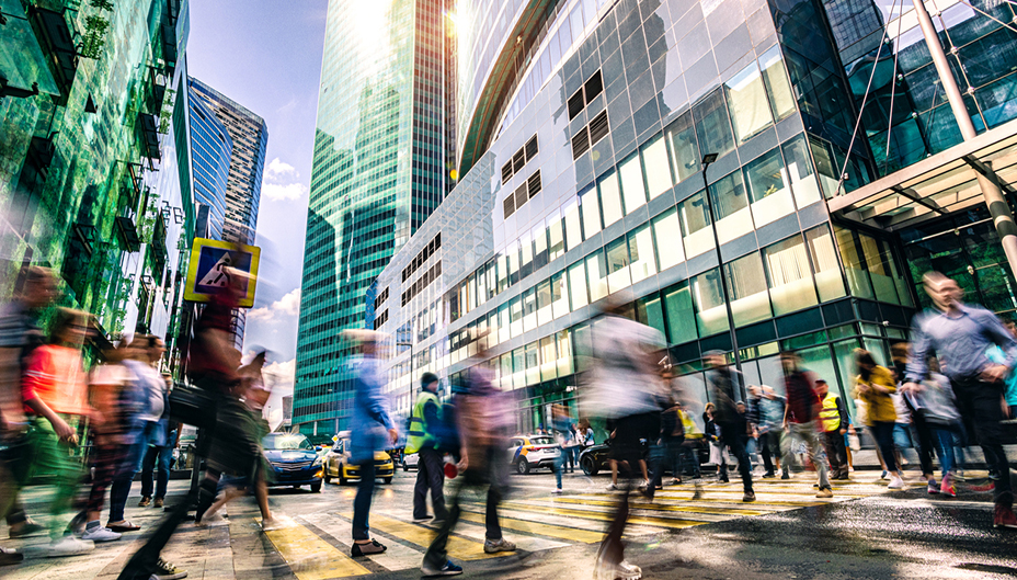 A blurred image of workers crossing a busy city street.