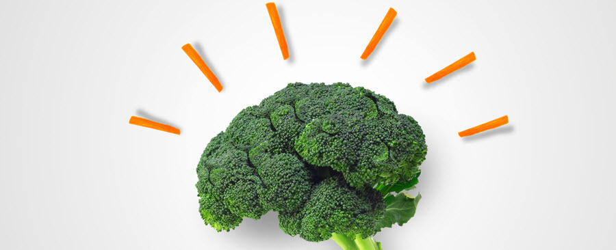 Close-up of a brain shaped broccoli with baby carrots surrounding it.