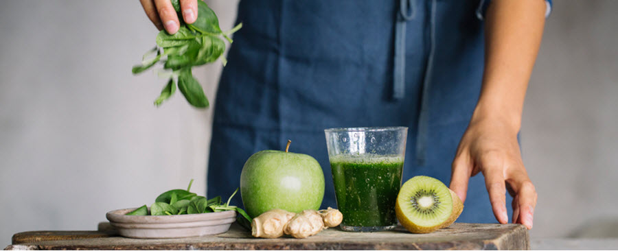 Woman displaying ingredients for a green smoothie