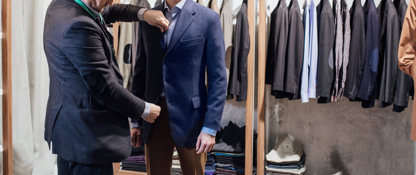 Tailor fitting a suit on a male model. 