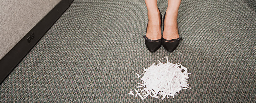 Femme debout derrière une pile de papier déchiqueté.