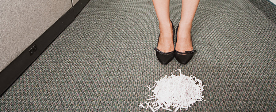 Woman standing behind a pile of shredded paper. 