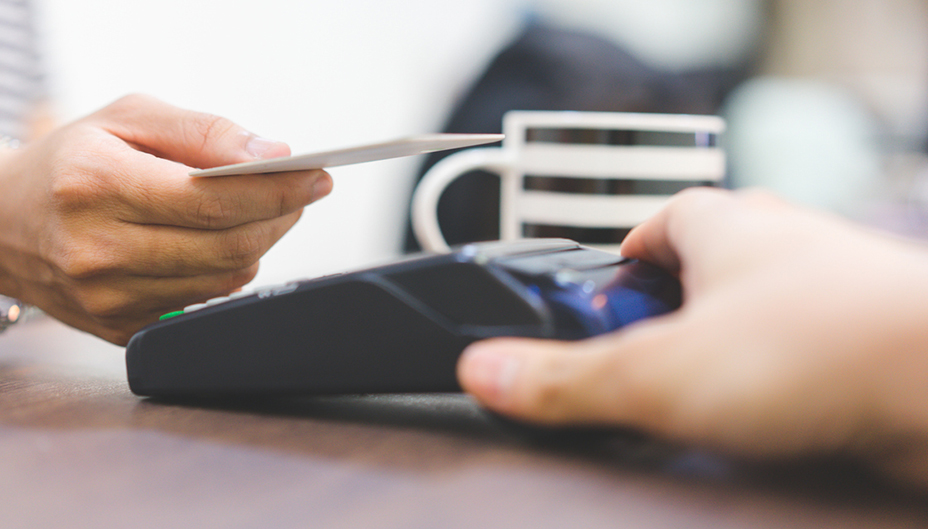 Unidentified person tapping their card to pay at a retail store.